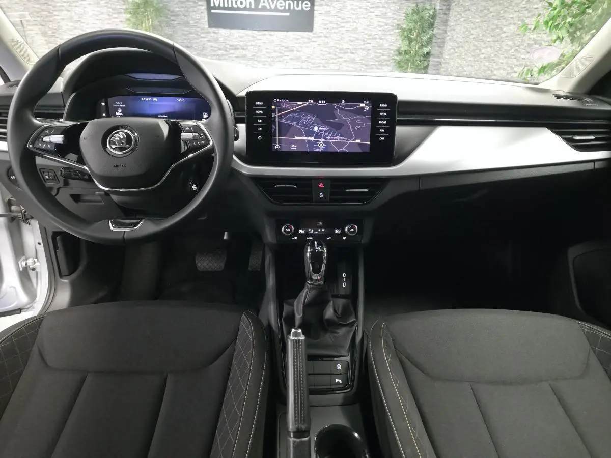 Vue intérieure avant du Skoda Kamiq 2023 avec tableau de bord noir, écran tactile central et volant multifonctions.