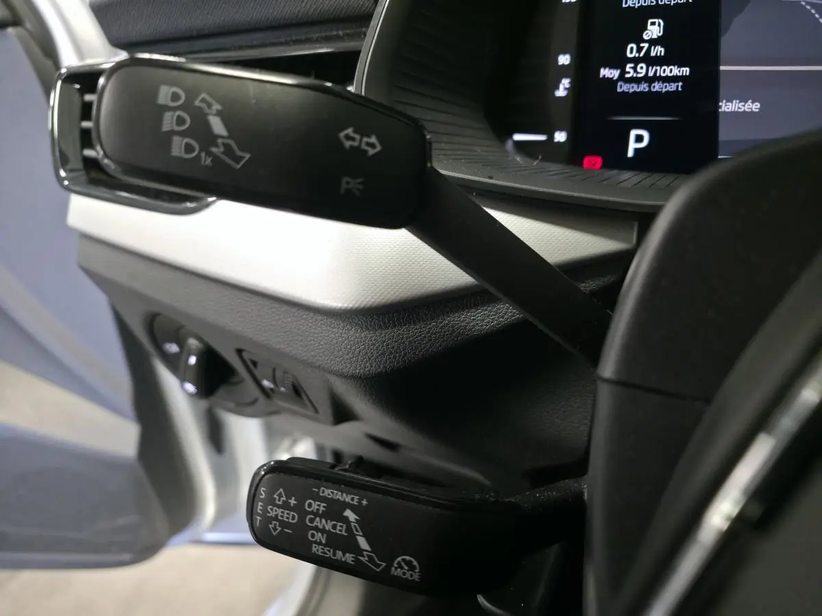 Gros plan sur les commandes au volant du Skoda Kamiq 2023, avec affichage digital et leviers multifonctions noirs.