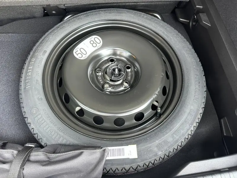 Roue de secours noire en acier dans le coffre d’un Renault Captur 1.8 E-Tech full hybrid 2026, détail intérieur.