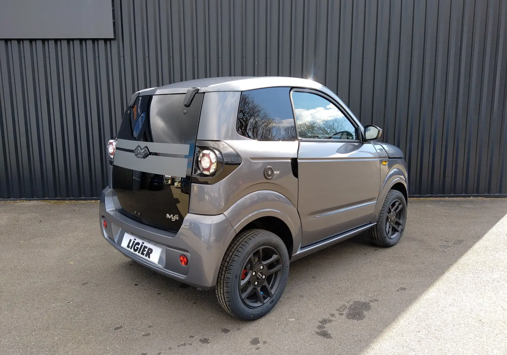 Vue 3/4 arrière droite d'une Ligier Myli REVO D+ MAX gris graphite avec vitres teintées et jantes noires.
