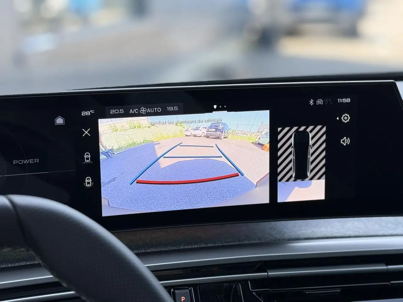 Vue intérieure sur l'écran tactile du Peugeot 5008 Hybrid noir Perla affichant la caméra de recul et l'aide au stationnement.