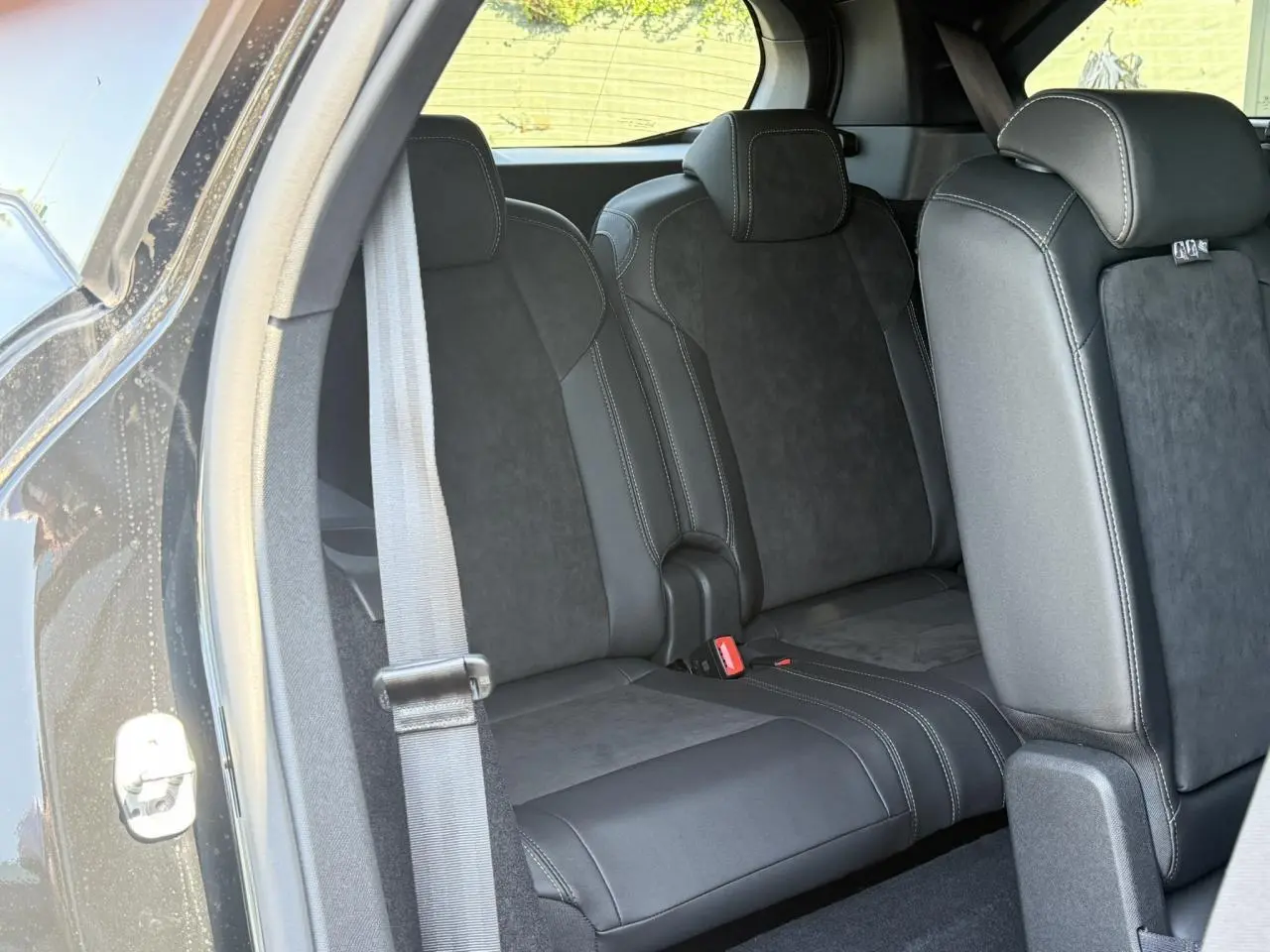 Vue intérieure côté gauche sur la banquette arrière en Alcantara noir du Peugeot 5008 Hybrid 2026 avec ceinture grise visible.