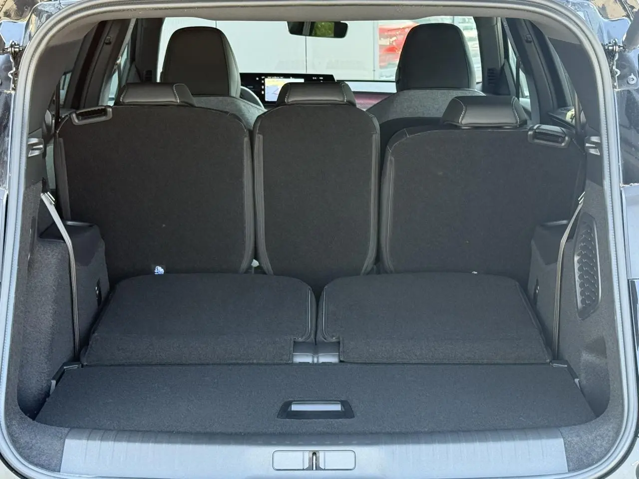 Vue arrière du coffre noir Perla du Peugeot 5008 Hybrid GT, montrant les sièges rabattus et l'espace de chargement.