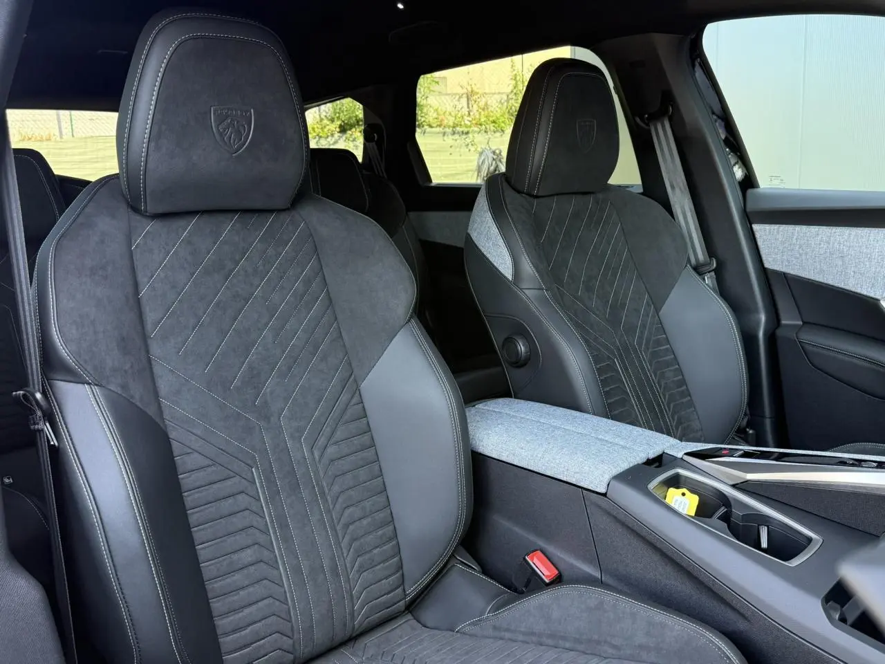 Vue rapprochée des sièges avant en Alcantara noir et tissu gris du Peugeot 5008 Hybrid GT, avec surpiqûres contrastées.