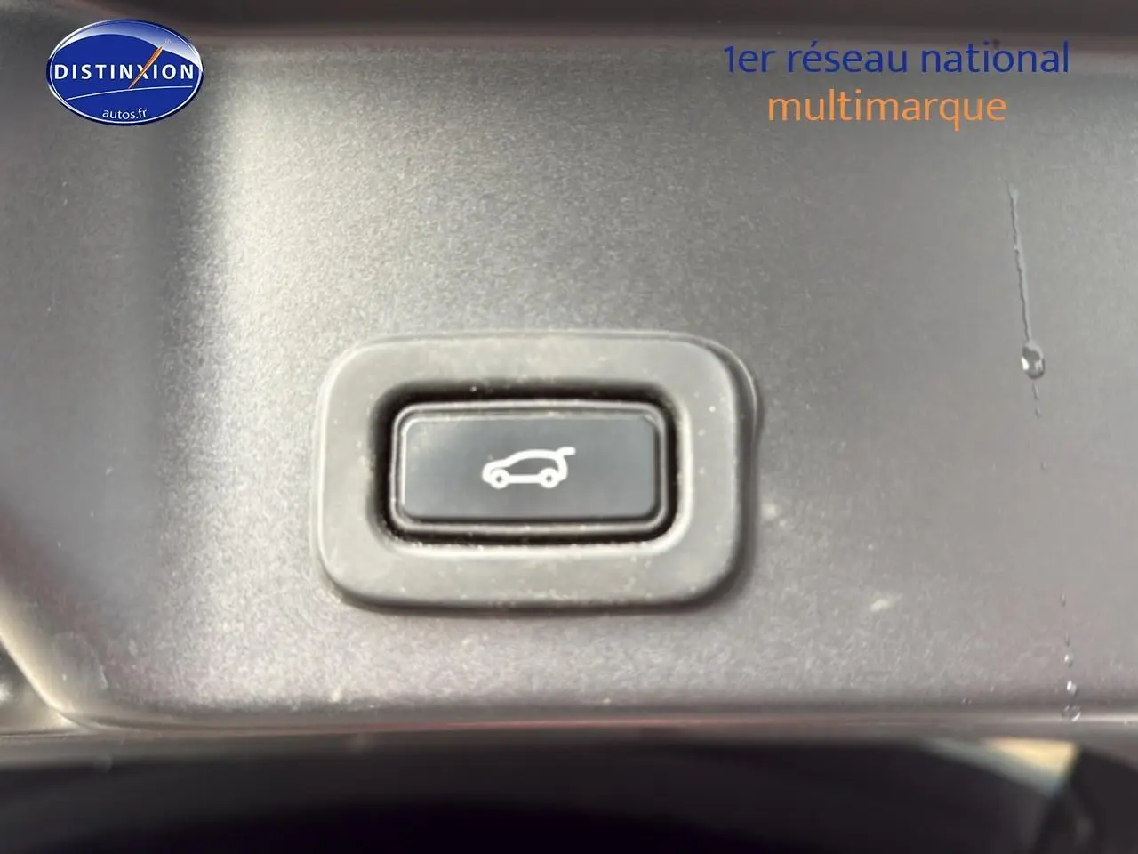 Bouton d'ouverture électrique du hayon sur le tableau de bord intérieur du Range Rover Evoque blanc et noir.
