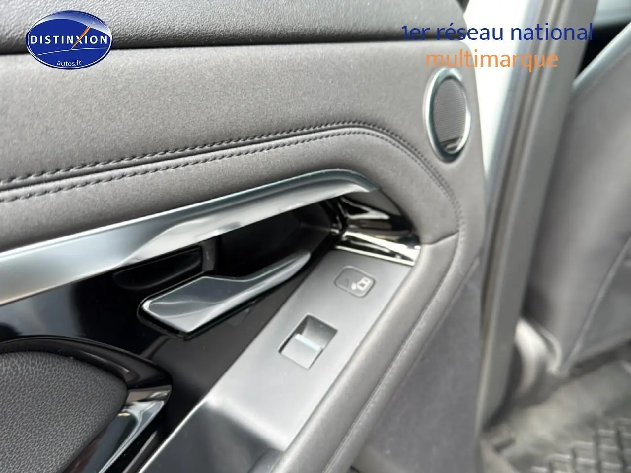Gros plan sur la poignée intérieure et les commandes de la porte côté gauche du Range Rover Evoque blanc et noir.