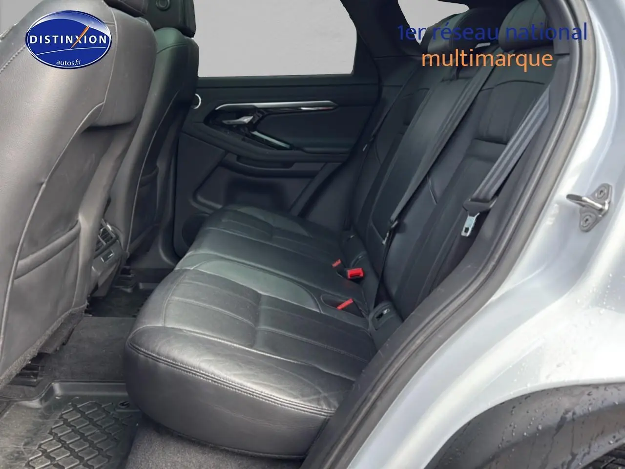 Vue intérieure côté droit sur la banquette arrière en cuir noir du Range Rover Evoque blanc, avec ceinture de sécurité visible.