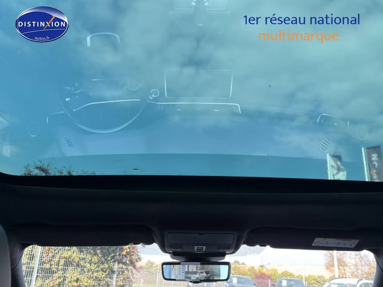 Vue intérieure du toit panoramique et du rétroviseur intérieur du Range Rover Evoque blanc, avec reflet extérieur visible.