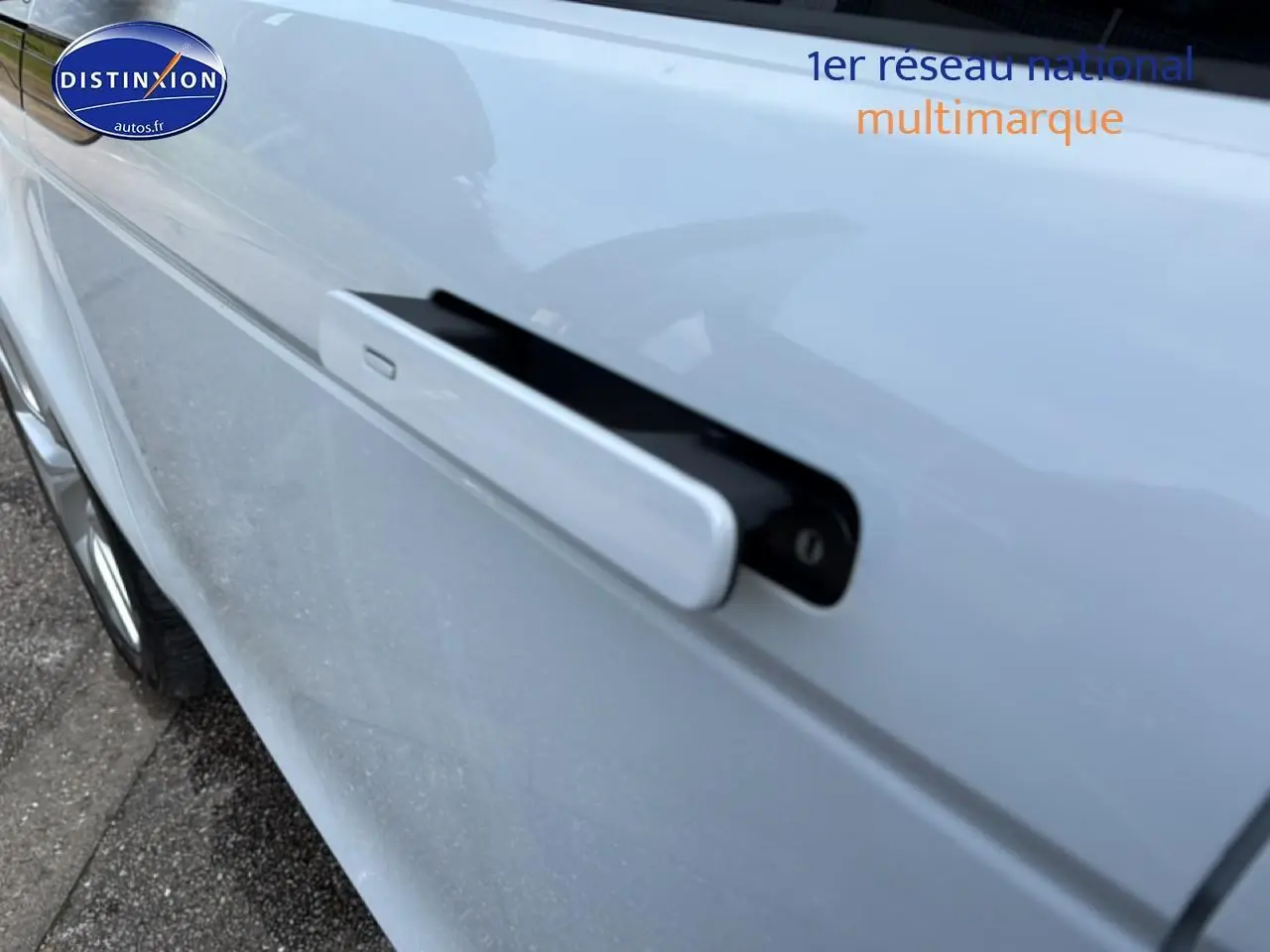 Gros plan sur la poignée de porte rétractable côté gauche d’un Range Rover Evoque blanc et noir.