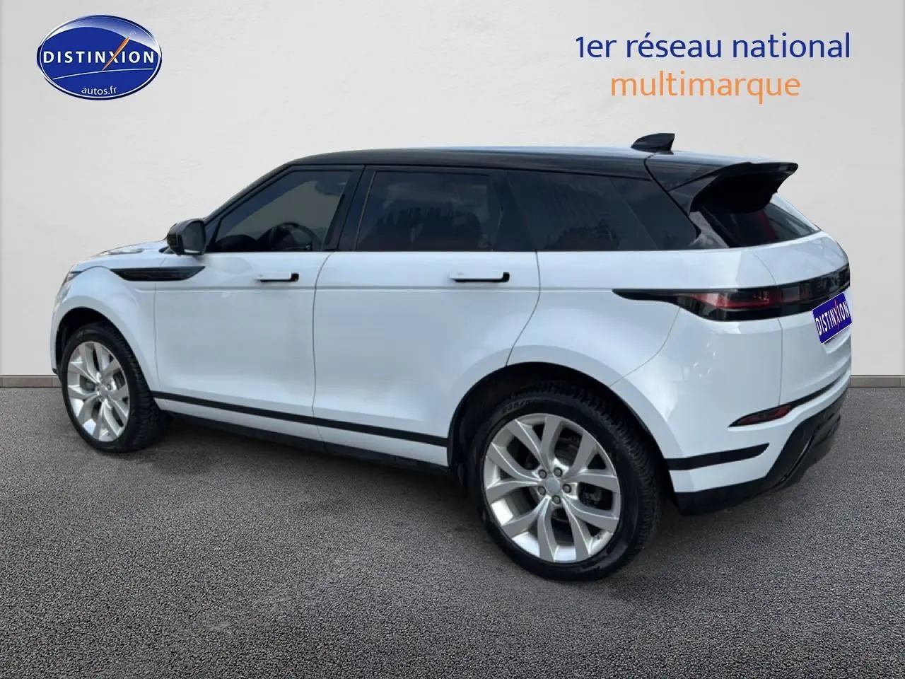 Vue de profil droit d’un Range Rover Evoque blanc avec toit noir et jantes alliage, arrière légèrement visible.