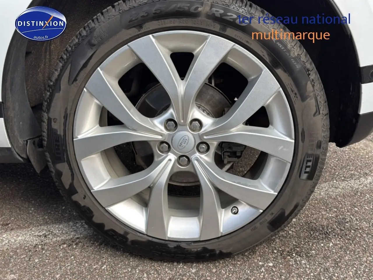Gros plan sur la jante alu argentée et le pneu Pirelli du côté avant droit d’un Range Rover Evoque blanc.