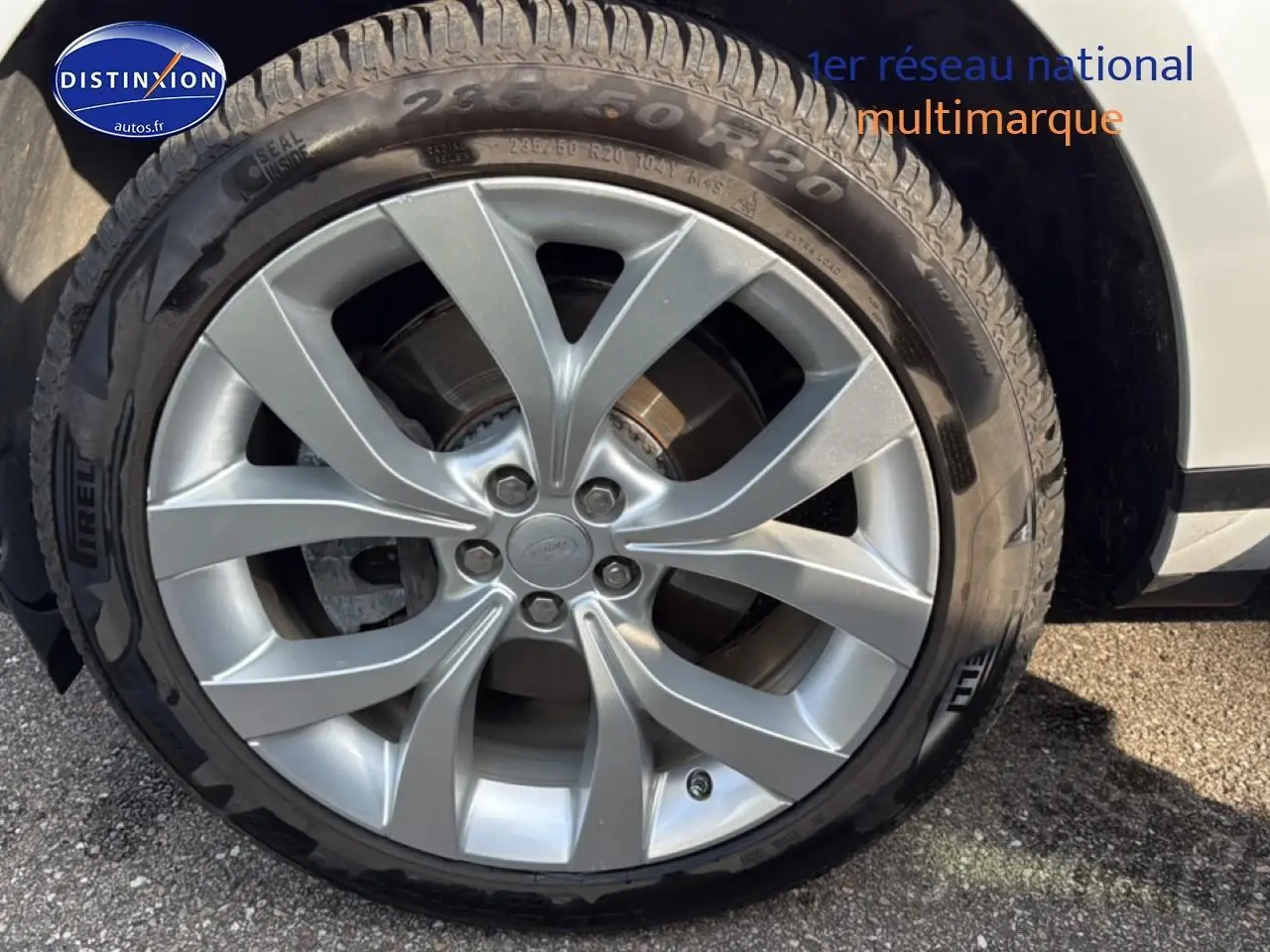 Gros plan sur la jante alu argentée et le pneu Pirelli du côté avant droit d’un Range Rover Evoque blanc.