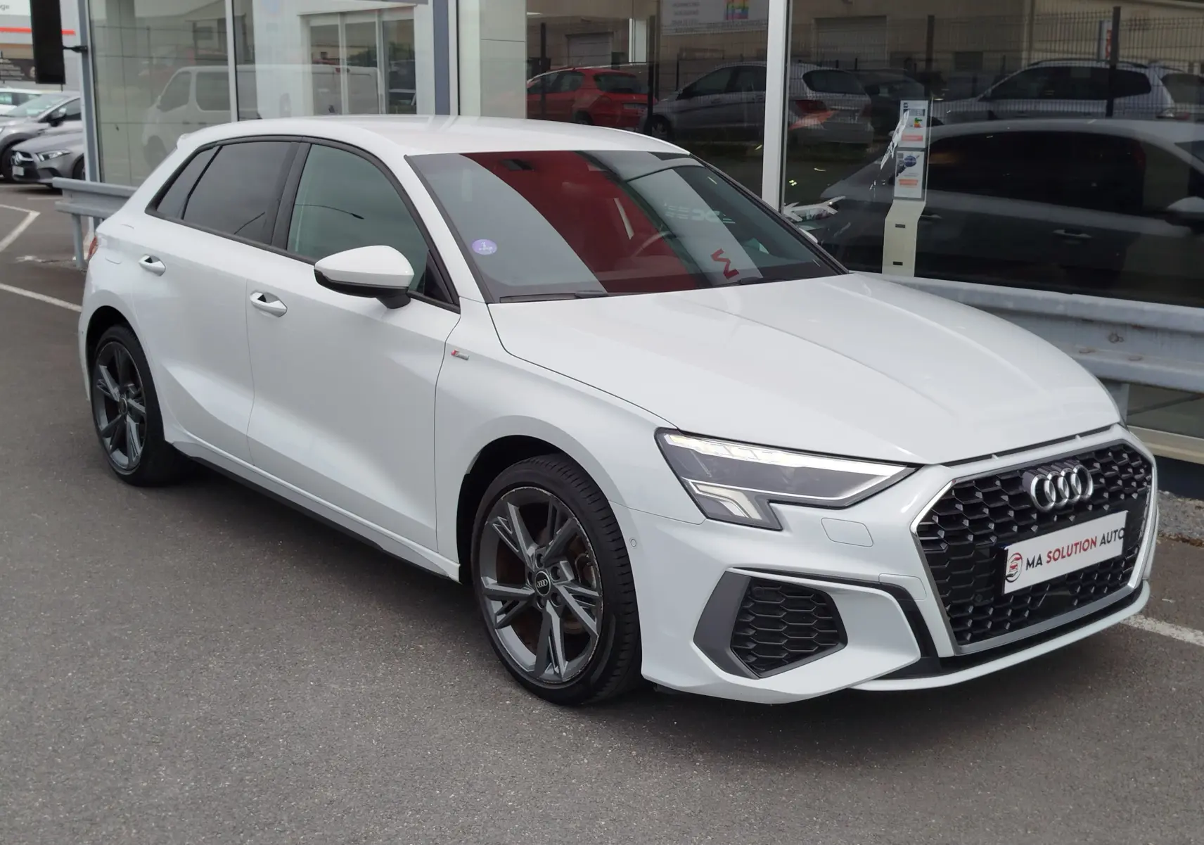 Audi A3 Sportback blanc Glacier métallisé vue 3/4 avant droit, avec calandre noire et jantes alliage foncé.