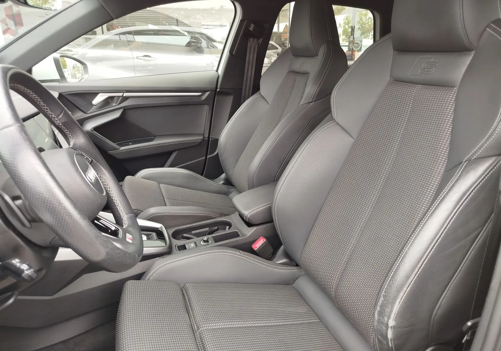 Vue intérieure côté conducteur de l'Audi A3 Sportback 30 TFSI S line 2022 avec sièges sport en cuir gris foncé.