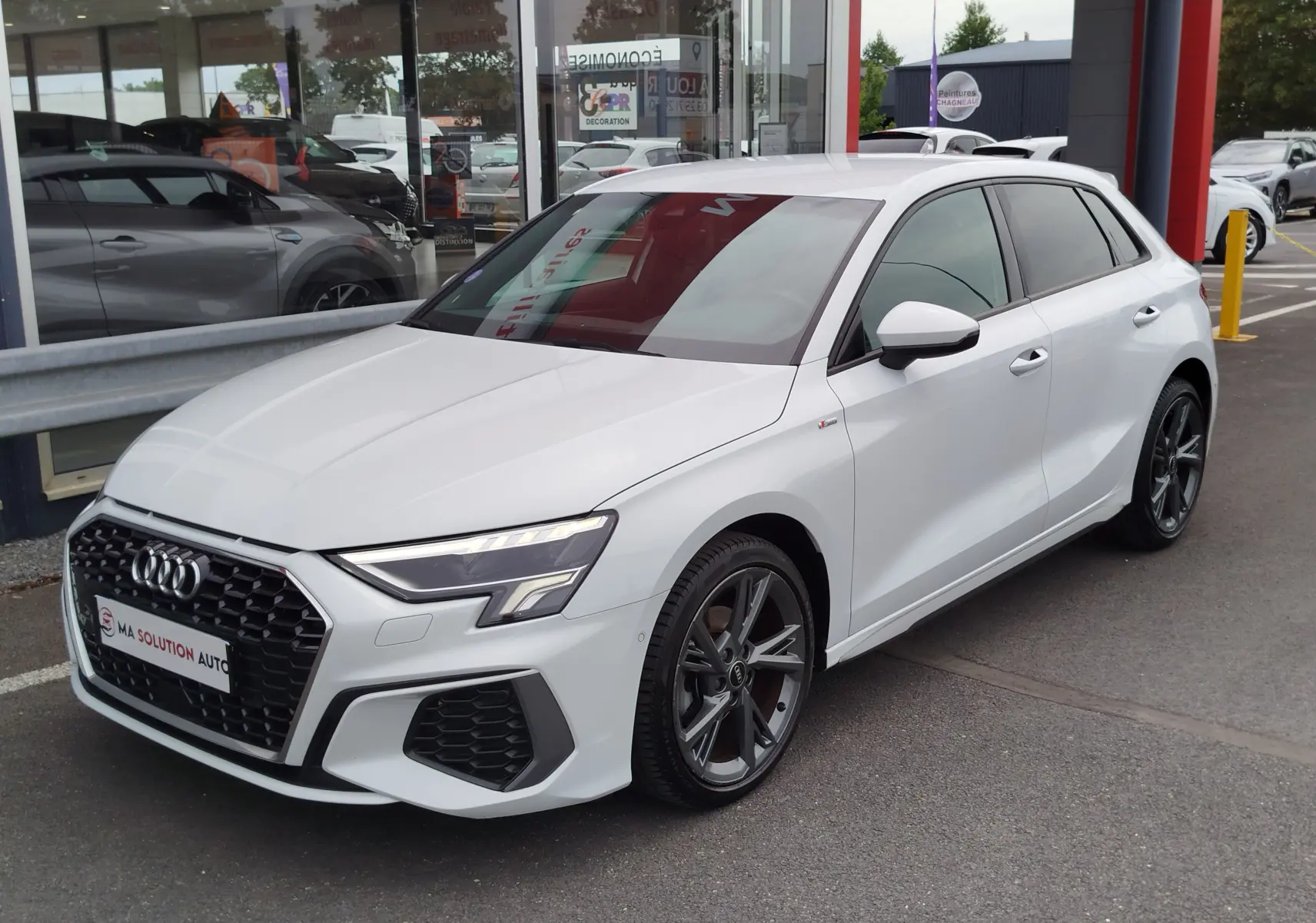 Audi A3 Sportback blanc Glacier métallisé vue 3/4 avant droit avec jantes alliage et calandre S line.