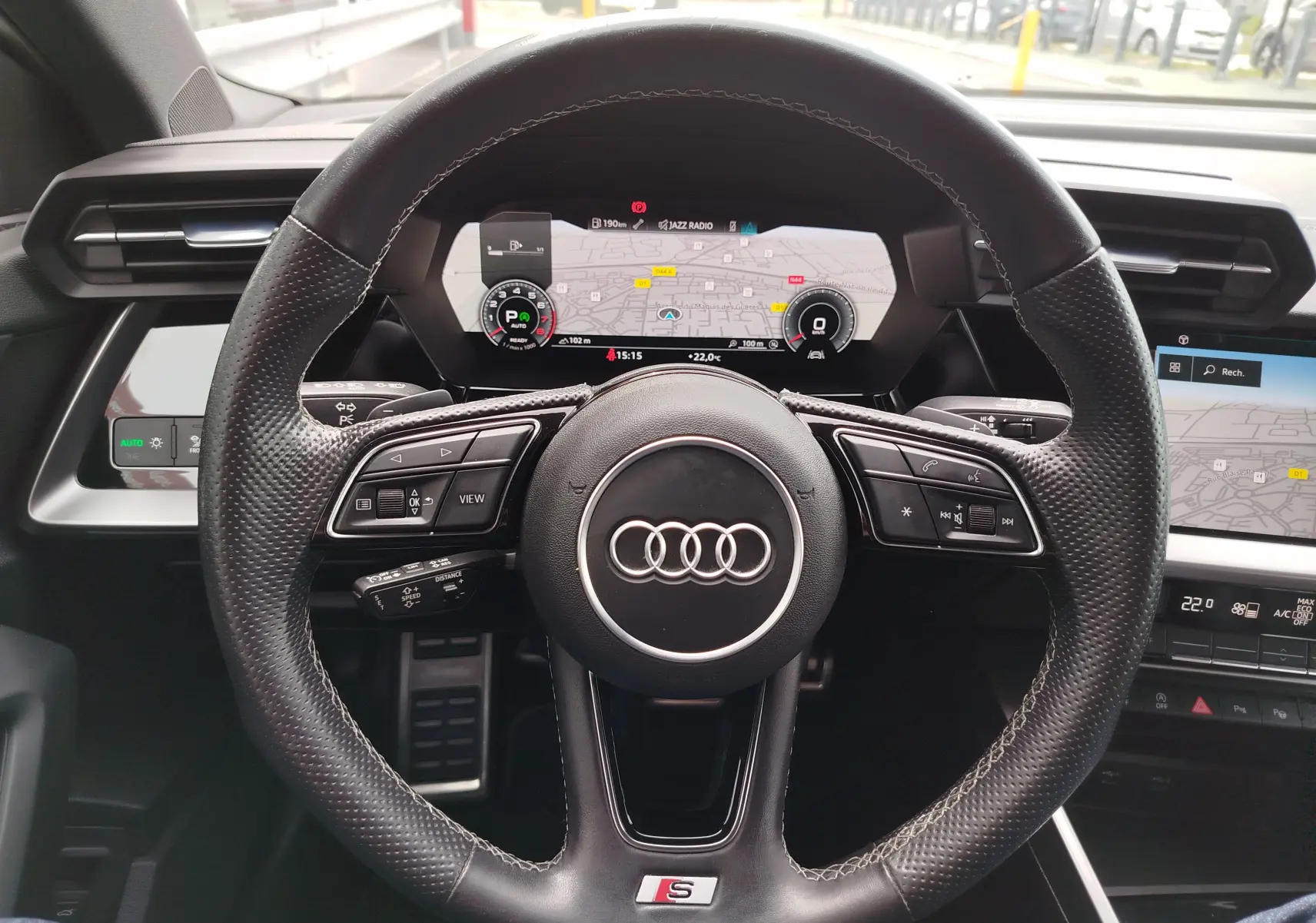 Vue centrée sur le volant cuir perforé de l'Audi A3 Sportback 30 TFSI S line avec tableau de bord numérique allumé.