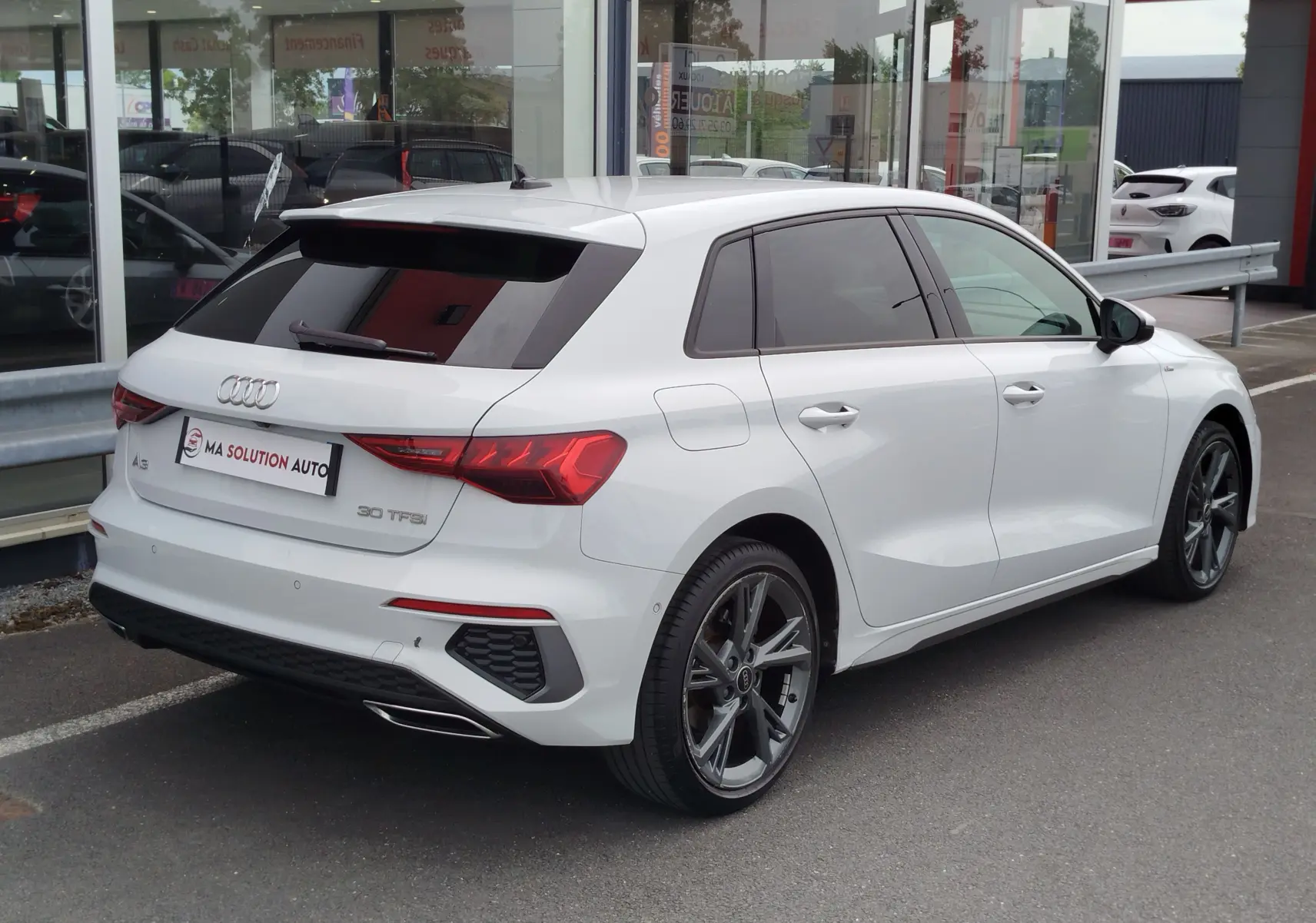 Audi A3 Sportback blanc Glacier métallisé vue 3/4 arrière droit, avec jantes alliage et vitres teintées.