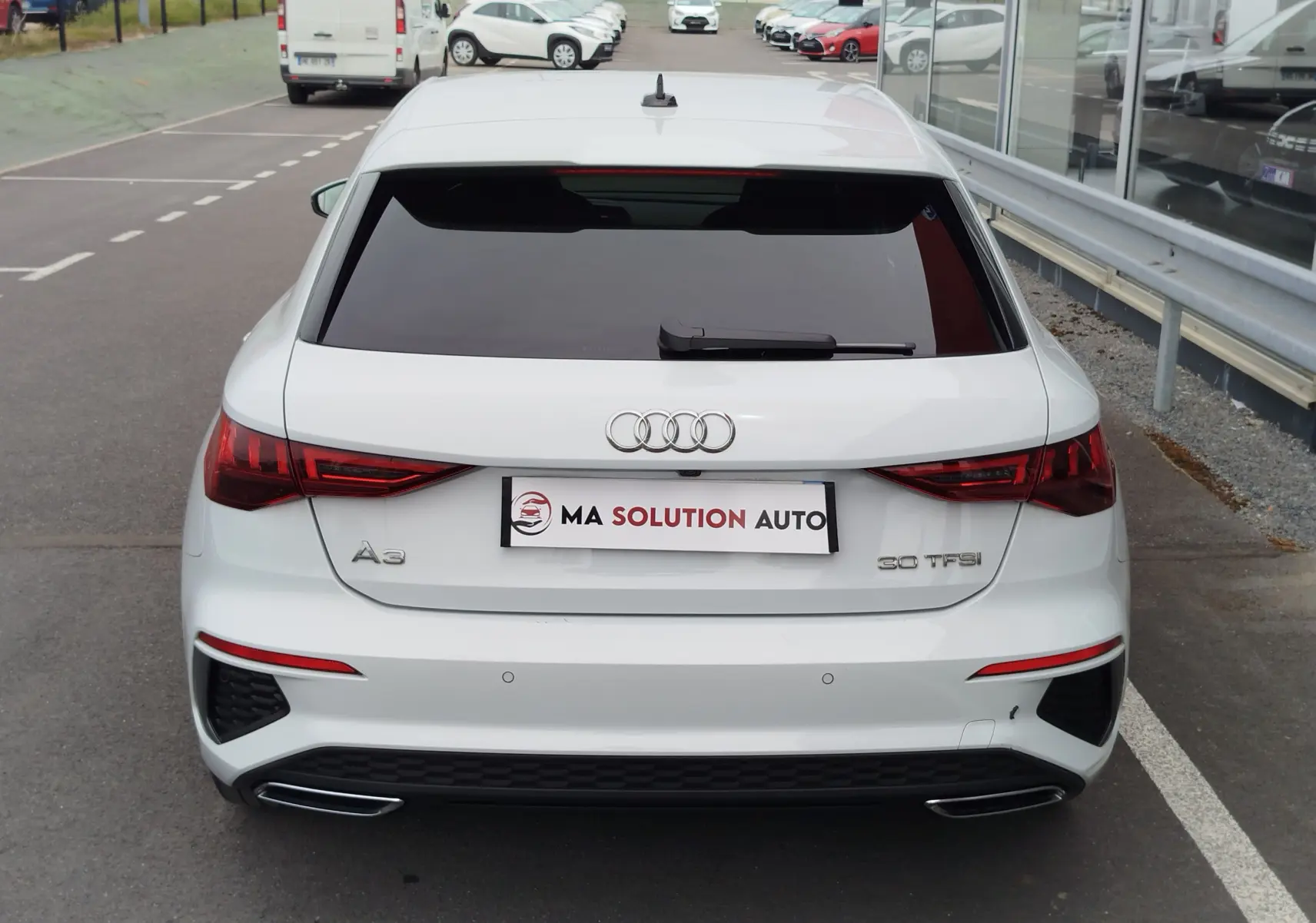 Vue arrière d'une Audi A3 Sportback blanc glacier métallisé, avec feux LED et double sortie d'échappement intégrée.