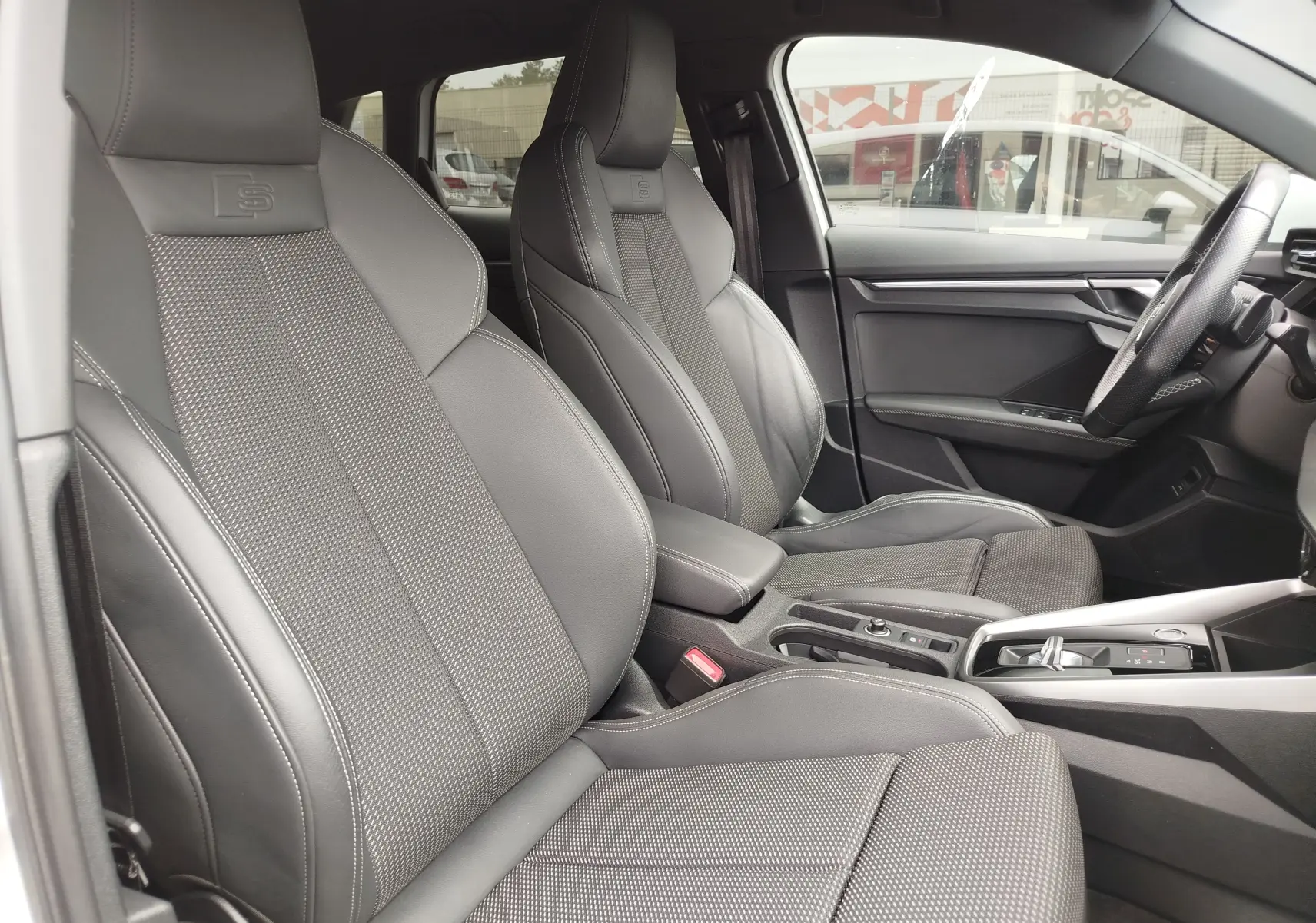Vue intérieure côté conducteur de l'Audi A3 Sportback 30 TFSI S line 2022 avec sièges sport en cuir gris foncé.