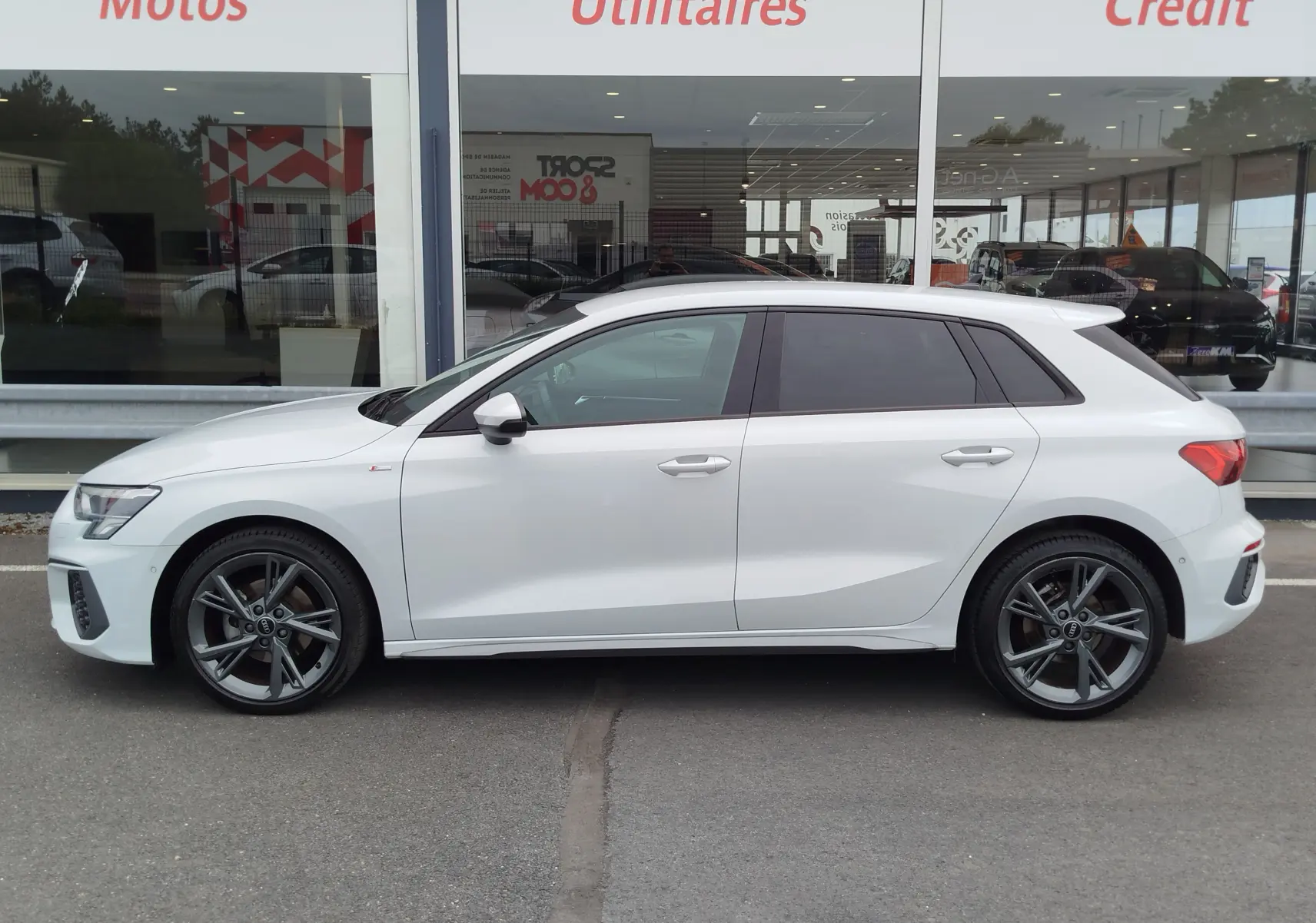 Audi A3 Sportback blanc Glacier métallisé vue de profil côté gauche, avec jantes alliage et vitres teintées.