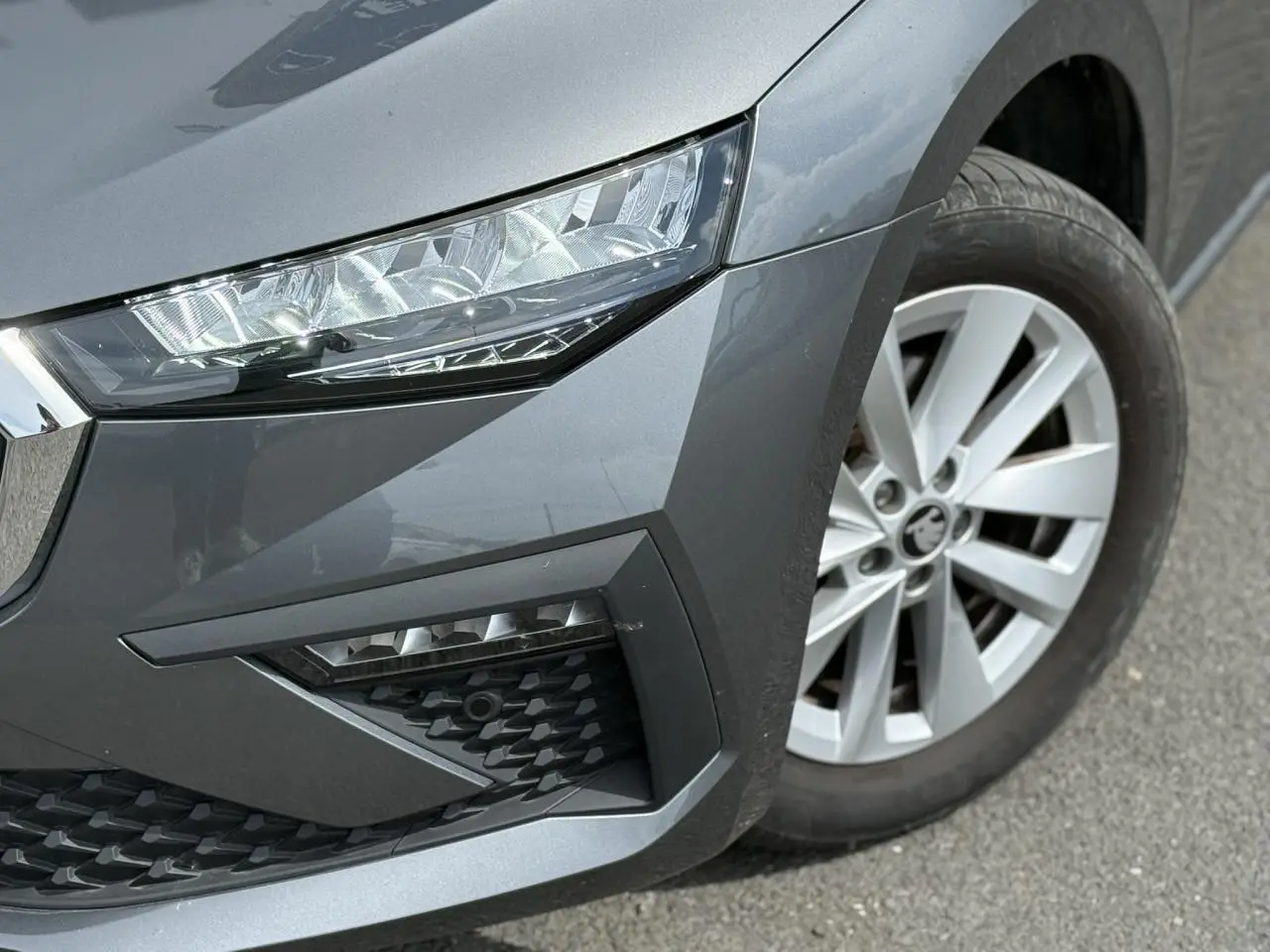 Gros plan sur l'avant droit gris graphite d'une Skoda Scala TSI 116, mettant en valeur le phare LED et la jante alliage.