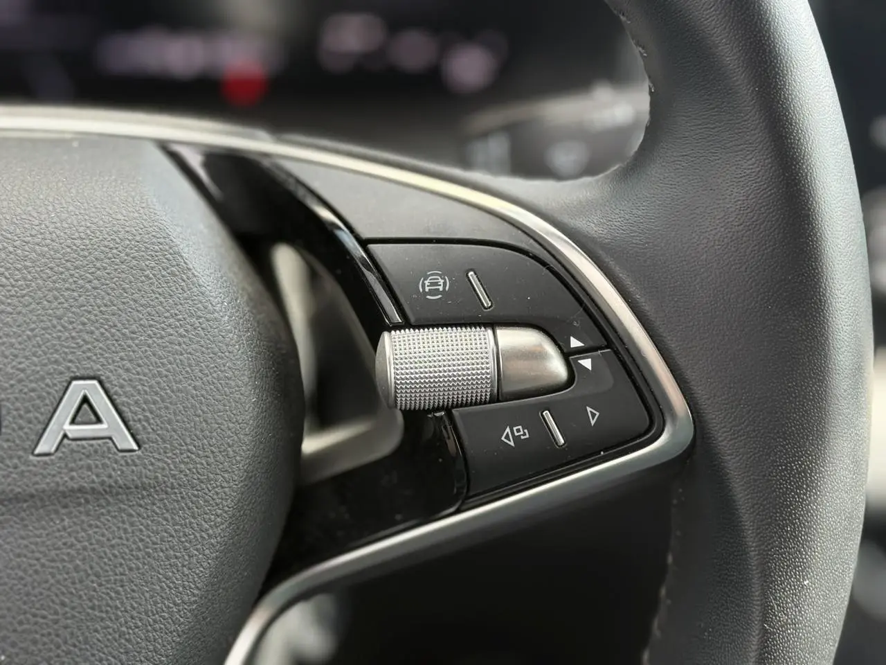Gros plan sur le volant cuir à deux branches de la Skoda Scala gris graphite, avec commandes multifonctions côté droit.