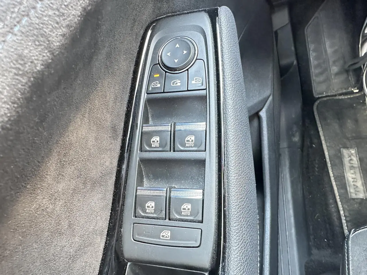 Gros plan sur les commandes de lève-vitres et rétroviseurs côté conducteur du Renault Austral 2024, intérieur noir.