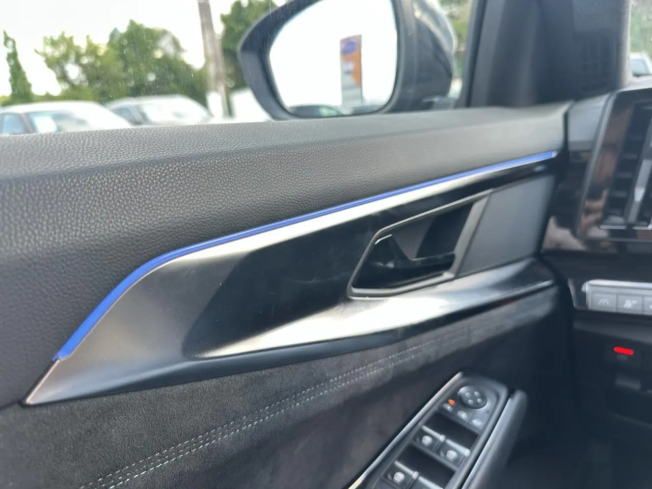Détail de la porte côté conducteur du Renault Austral 2024 bleu toit noir, avec commandes de vitres et insert décoratif bleu.
