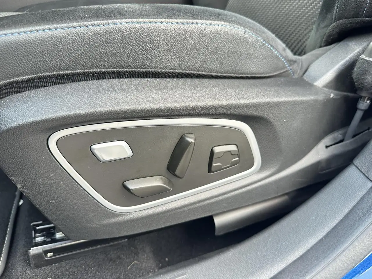 Gros plan sur les commandes électriques du siège conducteur du Renault Austral 2024 bleu toit noir.