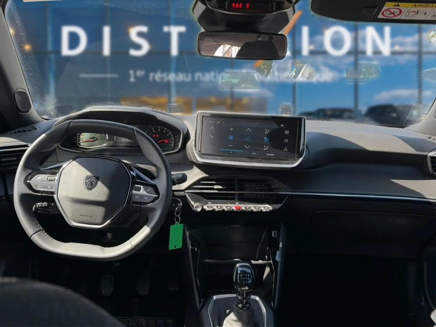 Vue intérieure avant du Peugeot 2008 gris 2025, volant multifonction, écran tactile et levier de boîte manuelle visibles.