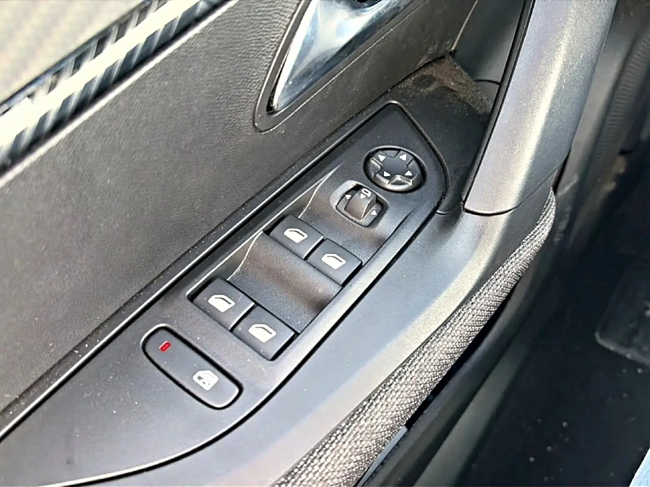 Gros plan sur les commandes de vitres électriques côté gauche d'une Peugeot 2008 gris, avec bouton de verrouillage activé.