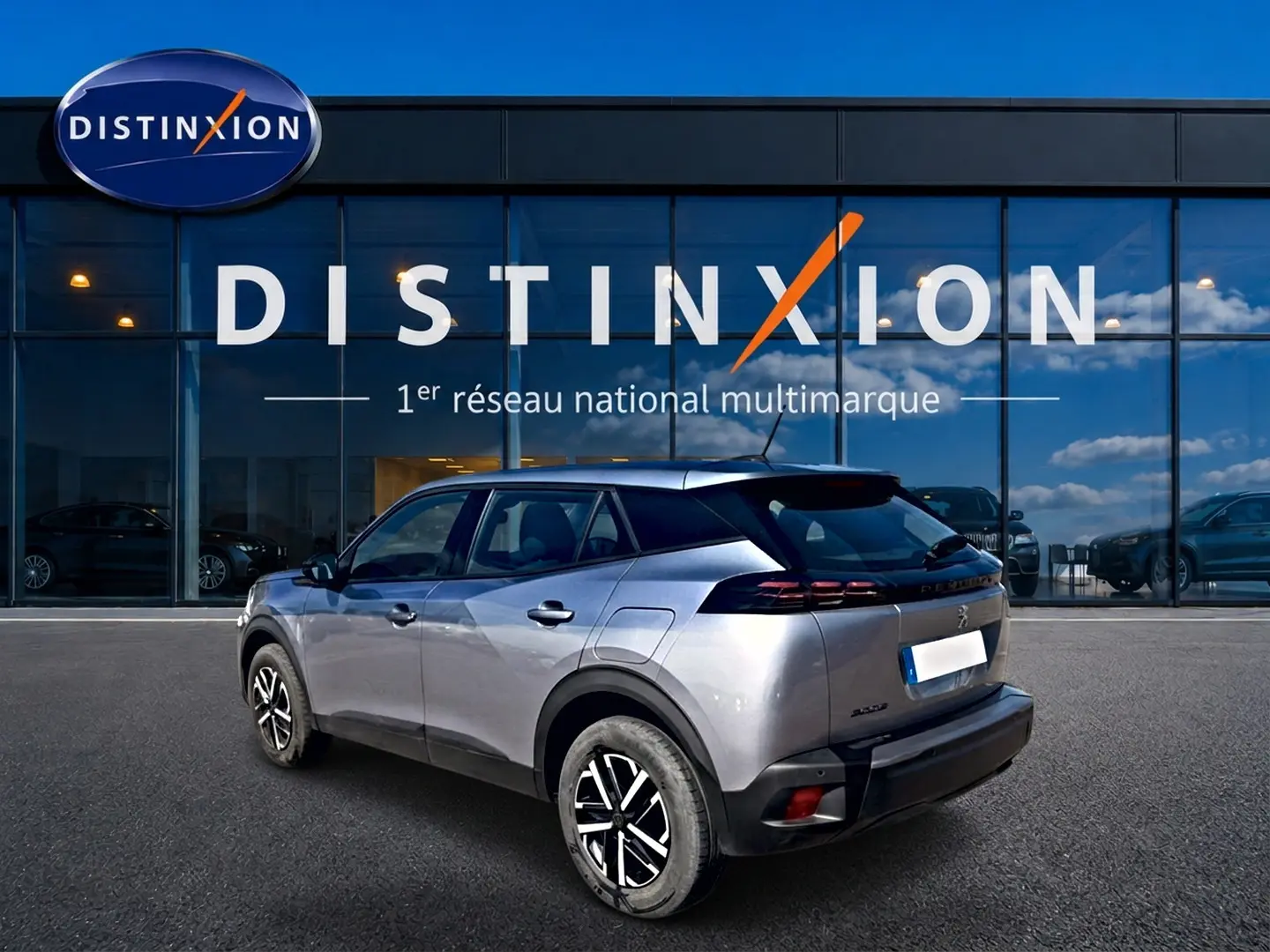 Peugeot 2008 gris en 3/4 arrière droit, avec toit noir et feux arrière LED, devant une vitrine Distinxion.