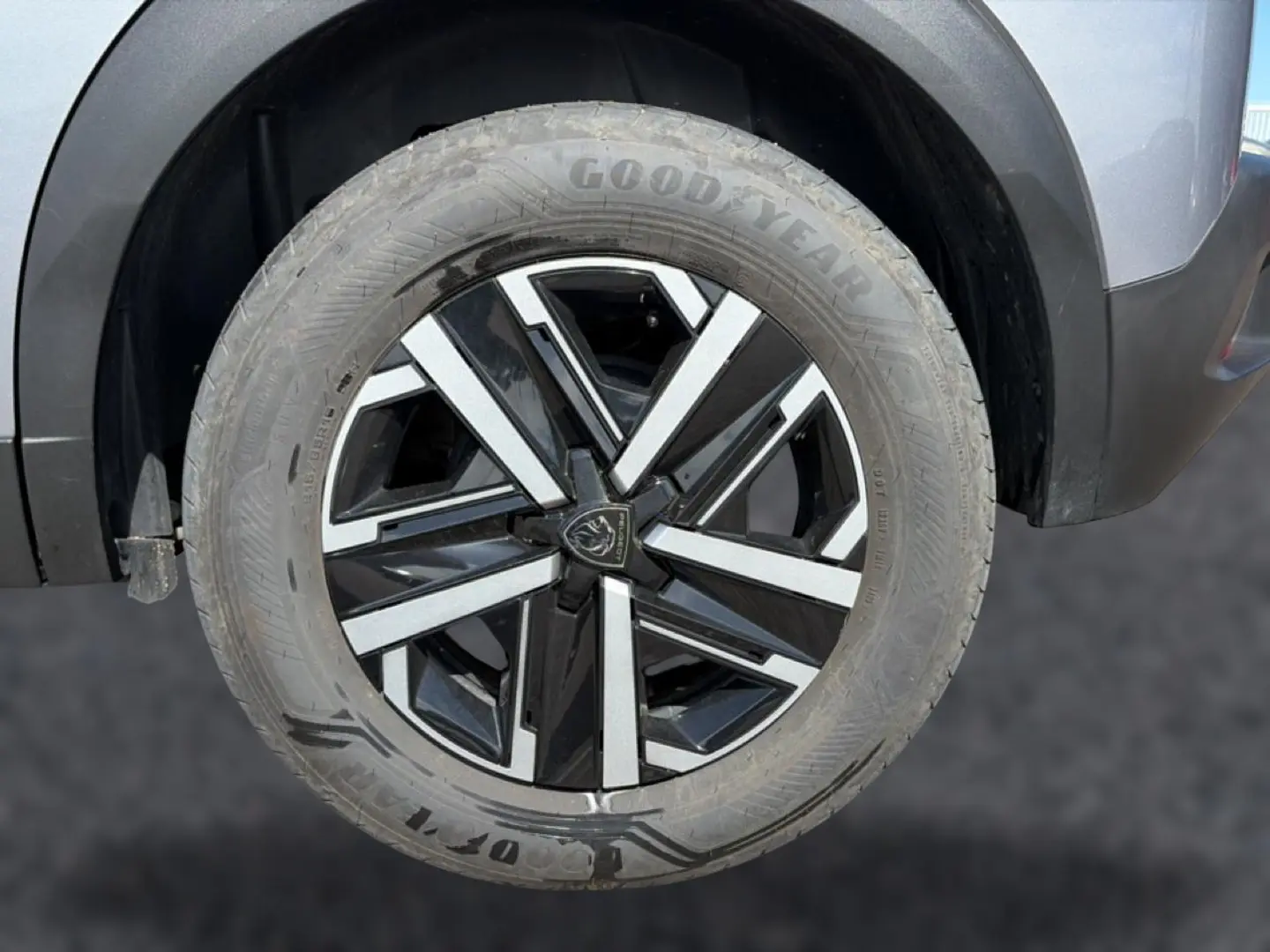 Gros plan sur la roue avant gauche du Peugeot 2008 gris, avec jante alliage noire et argentée au design moderne.
