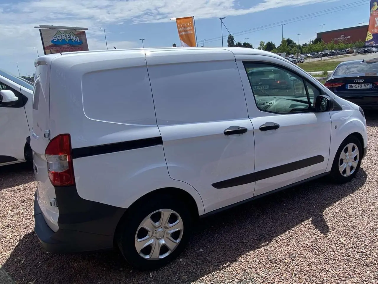 Ford Tourneo Courier blanc vu de trois quarts arrière droit, fourgon utilitaire avec porte latérale coulissante et enjoliveurs cache moyeu.