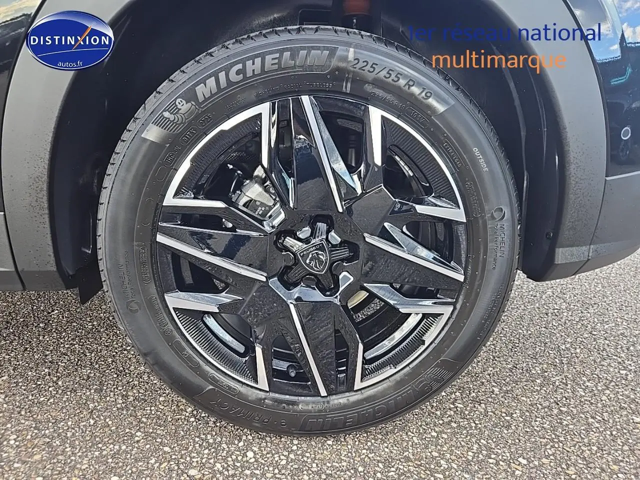 Gros plan sur la jante alu noire et chromée avec logo Peugeot d’un SUV 3008 noir, pneu Michelin visible.