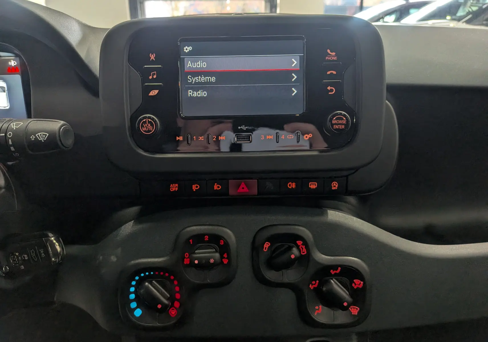 Vue rapprochée du tableau de bord de la Fiat Panda 1.0 Hybrid 2025 avec écran tactile et commandes de climatisation.