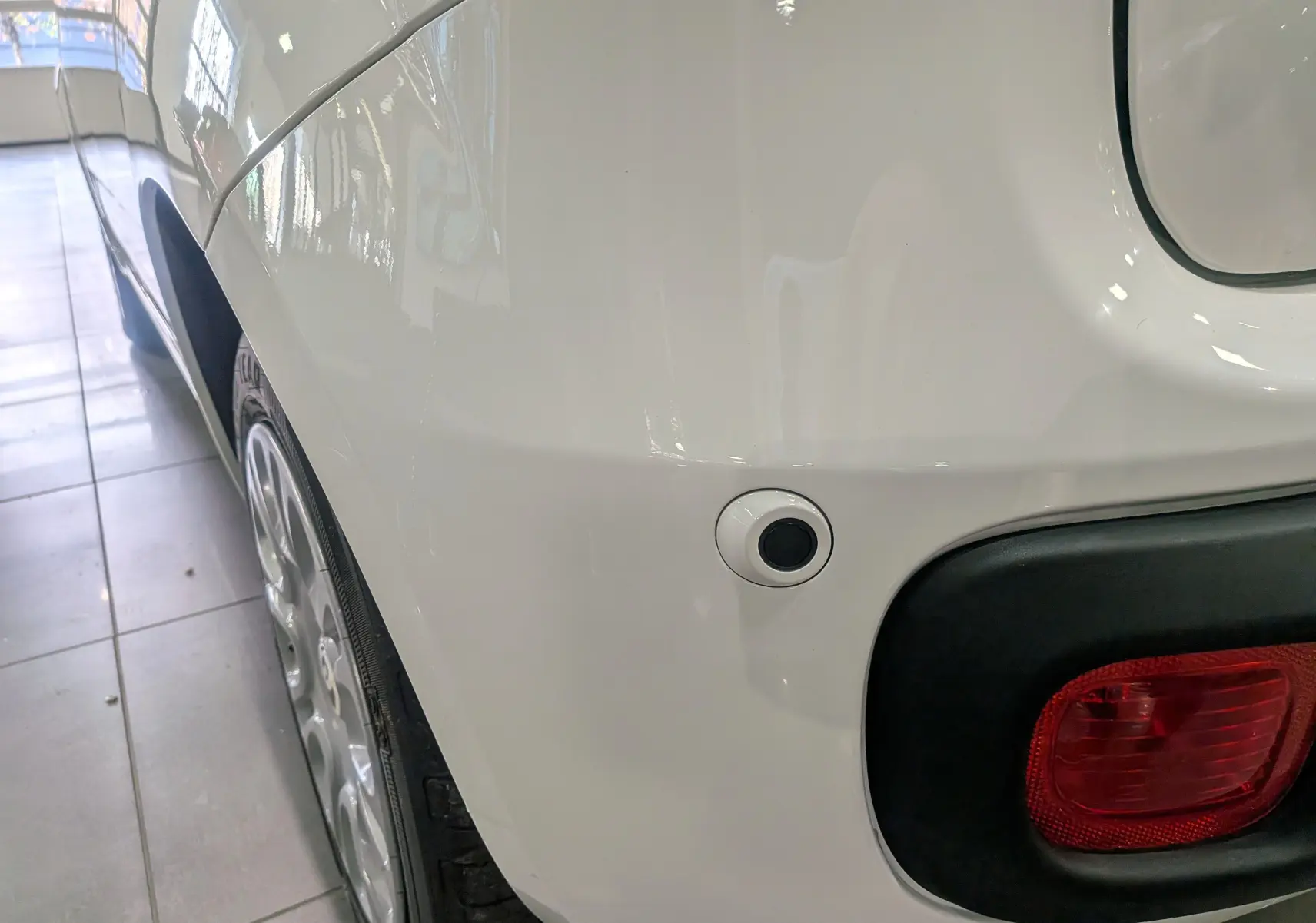 Gros plan sur l’aile arrière gauche blanche Gelato d’une Fiat Panda 1.0 Hybrid 2025 avec feu arrière et capteur de stationnement.