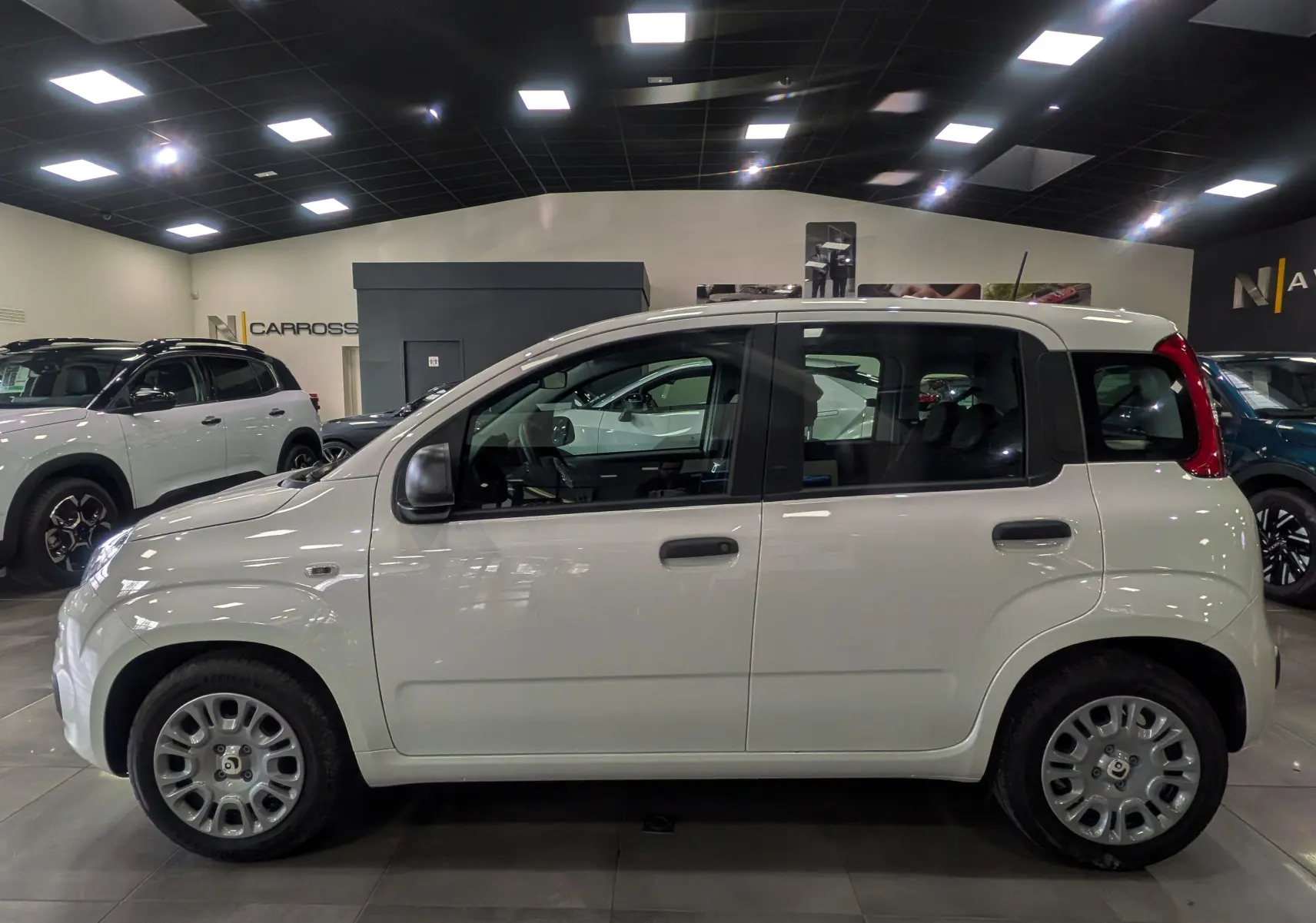 Vue de profil côté gauche d'une Fiat Panda 1.0 70 CH Hybrid City blanche Gelato en showroom.