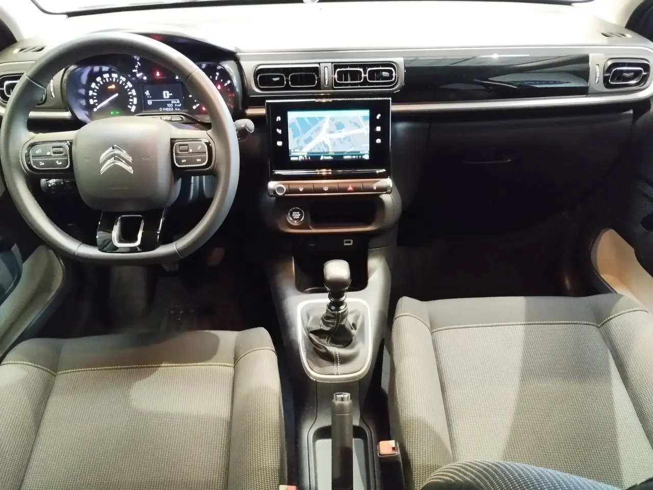 Vue intérieure avant de la Citroën C3 2024 avec tableau de bord noir brillant, volant multifonction et écran tactile central.