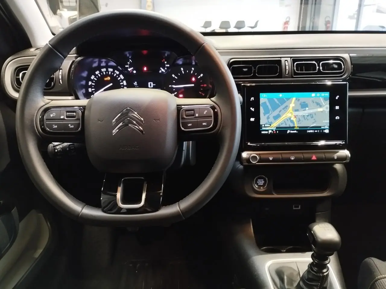 Vue intérieure frontale du poste de conduite de la Citroën C3 2024 avec volant multifonction et écran tactile de navigation.