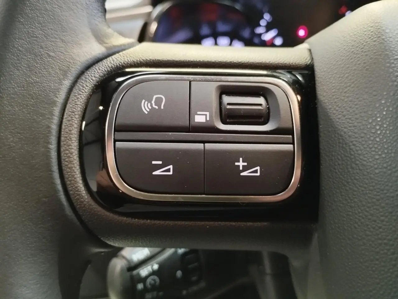 Gros plan sur les commandes au volant noir brillant de la Citroën C3 2024, boutons de réglage du volume et appels.