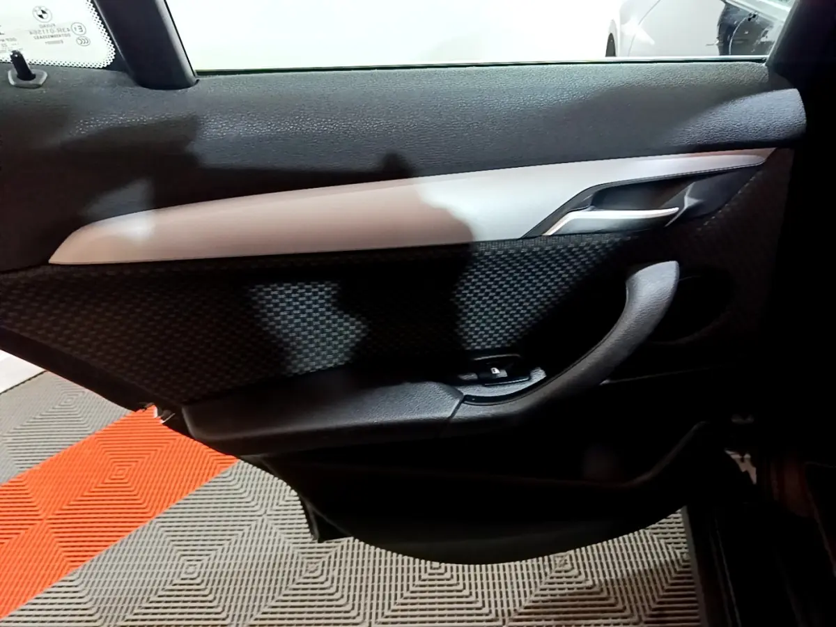 Vue rapprochée de la porte intérieure côté gauche noire avec insert gris et poignée alu d’une BMW X2 2023.