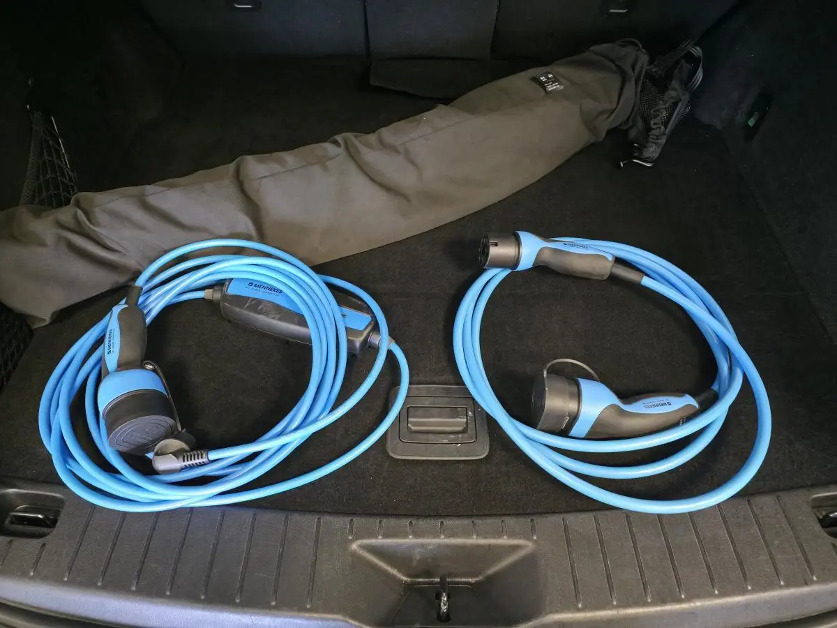 Vue du coffre noir du Mazda CX-60 gris avec deux câbles de recharge bleu clair enroulés.