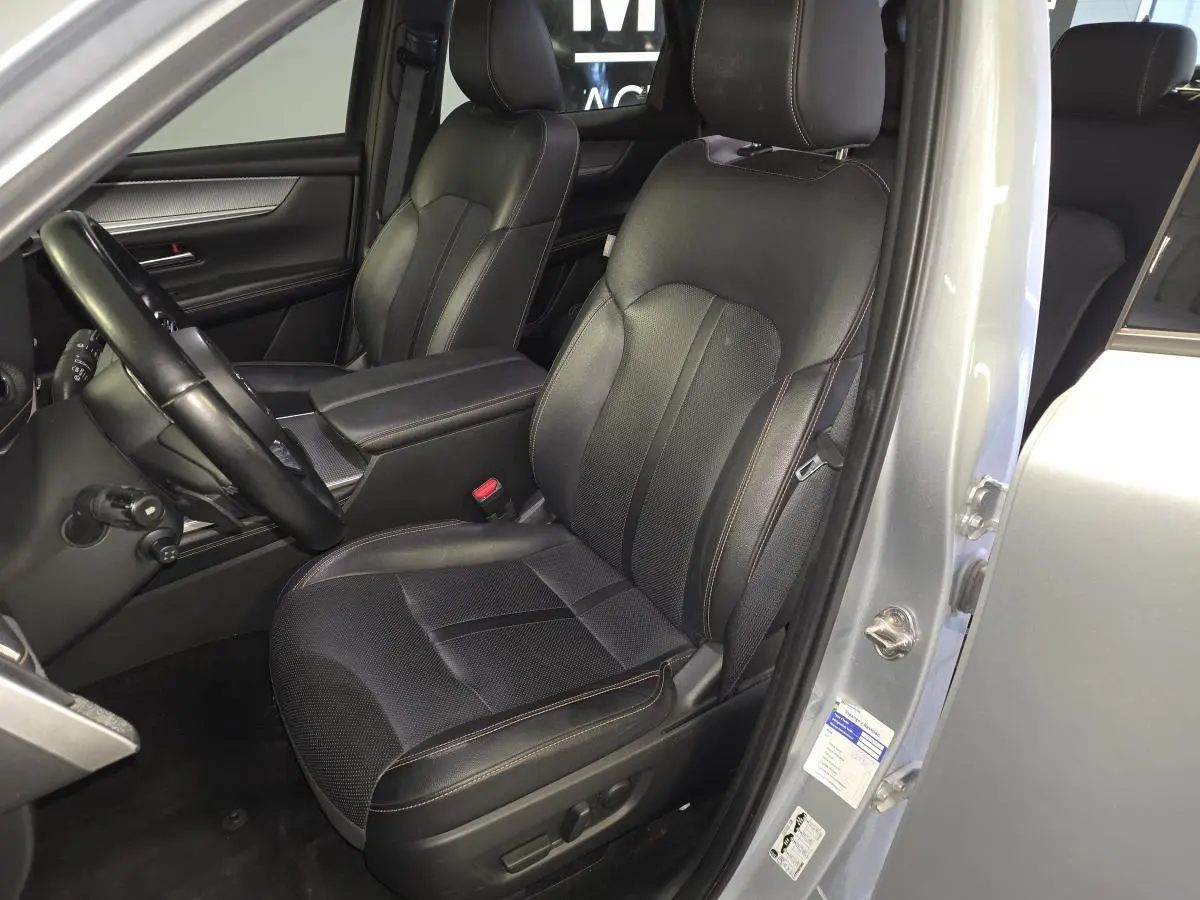 Vue intérieure côté conducteur du Mazda CX-60 gris, sièges cuir noir avec surpiqûres bronze et volant multifonction.