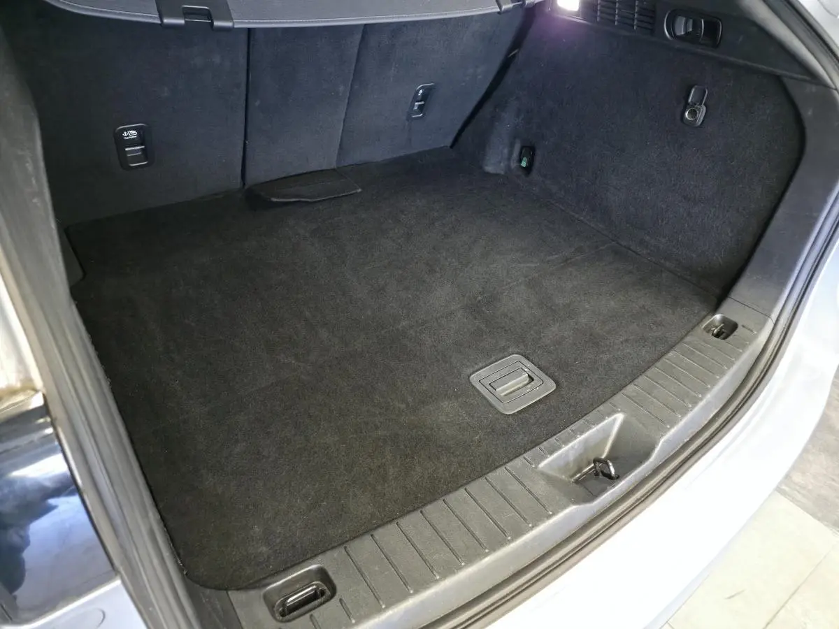 Vue rapprochée du coffre gris clair du Mazda CX-60 2.5 e-Skyactiv PHEV, montrant le tapis de sol et les fixations.