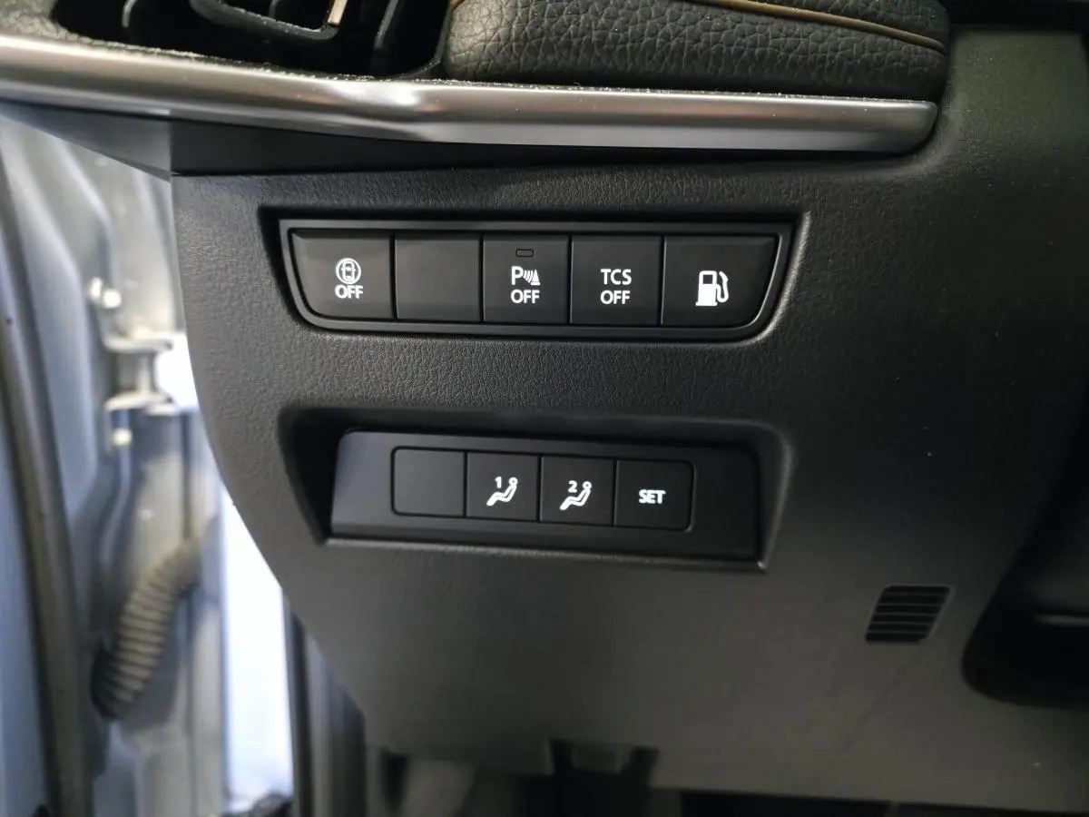 Gros plan sur les commandes noires côté gauche du tableau de bord du Mazda CX-60 gris 2023, boutons d'assistance et réglages mémoire.