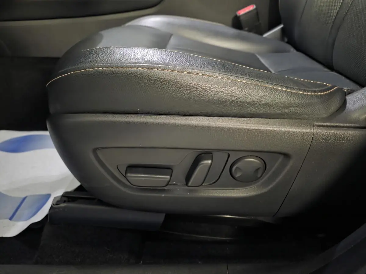 Gros plan sur les commandes électriques du siège avant en cuir noir avec surpiqûres bronze du Mazda CX-60 gris.