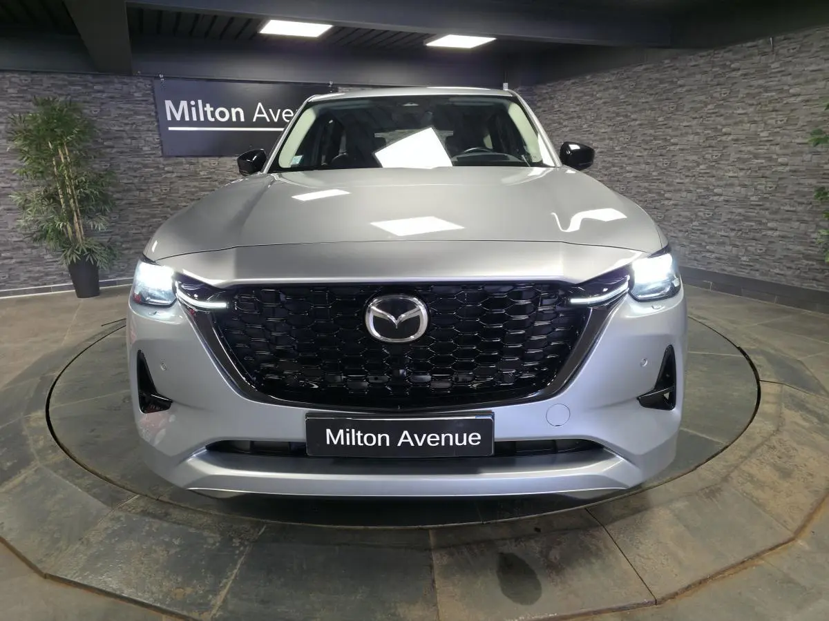 Vue frontale d'un Mazda CX-60 gris Sonic Silver avec calandre noire nid d'abeille et phares LED allumés.