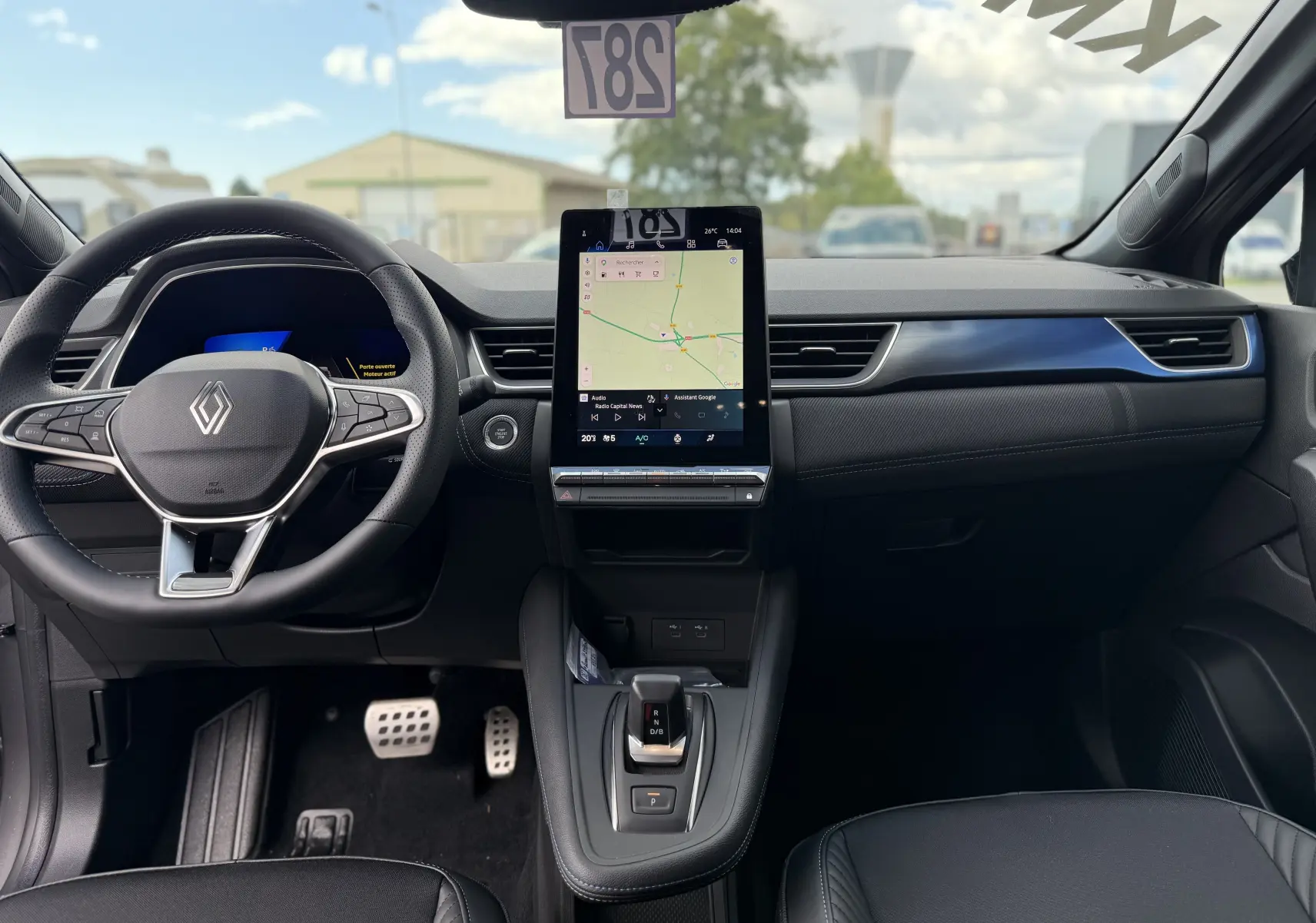 Vue intérieure frontale du tableau de bord du Renault Symbioz gris cassiopée, avec écran tactile central et volant multifonction.