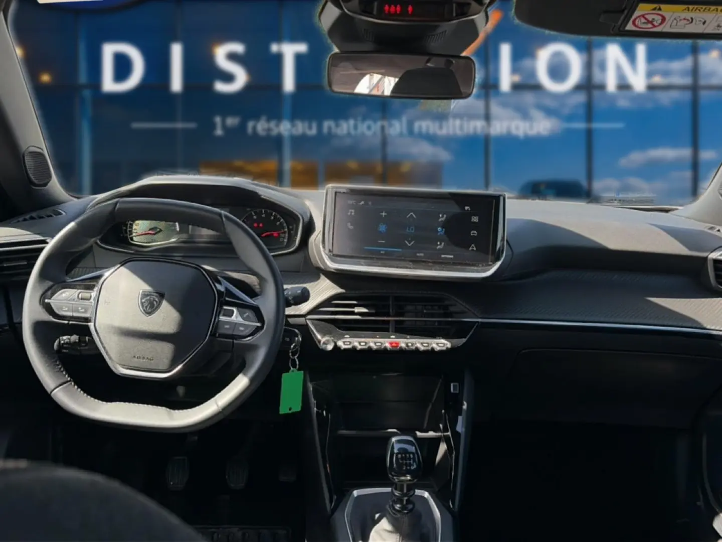 Vue intérieure du tableau de bord du Peugeot 2008 gris 2025, avec volant multifonction et écran tactile central.
